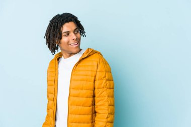 Genç melez adam gülümseyen, neşeli ve keyifli bir şekilde yana bakıyor..