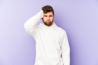 Mor arka planda izole edilmiş genç beyaz adam yorgun ve uykulu ellerini başının üstünde tutuyor..
