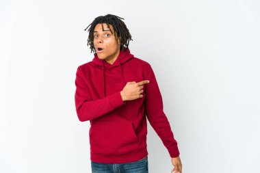 Genç Afrikalı Amerikalı Rasta adam gülümsüyor ve boş alanda bir şey gösteriyor..