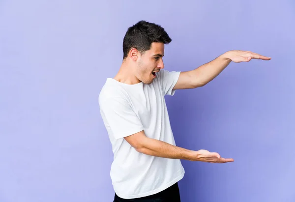 Jovem Caucasiano Isolado Fundo Roxo Chocado Surpreso Segurando Espaço Cópia — Fotografia de Stock