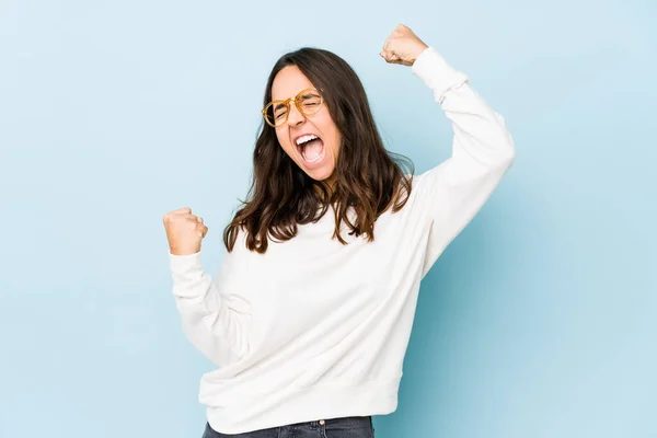 Young mixed race hispanic woman isolated raising fist after a victory, winner concept.