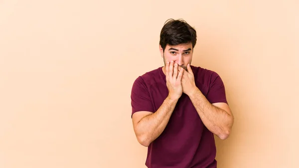 Ung Man Isolerad Beige Bakgrund Täcker Munnen Med Händerna Ser — Stockfoto