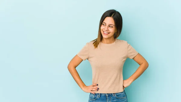 Jovem Mulher Isolada Fundo Azul Confiante Mantendo Mãos Nos Quadris — Fotografia de Stock