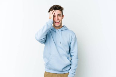 Beyaz arka planda izole edilmiş genç beyaz bir adam yüzünün yarısını palmiye ile örterek eğleniyor..