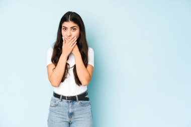 Mavi arka planda elleri endişeli görünen genç Hintli kadın..