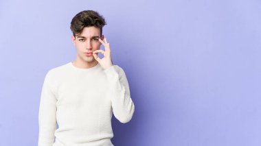 Mor arka planda izole edilmiş genç, beyaz bir adam dudaklarında parmaklarıyla bir sır saklıyor..