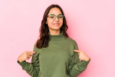 Genç, Latin kökenli bir kadın tişört fotokopi alanını elle işaret ediyor, gururlu ve kendinden emin.