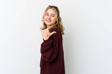 Beyaz arka plandaki genç beyaz kadın başparmak uzakta, gülüyor ve kaygısız..