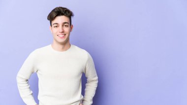 Mor arka planda izole edilmiş beyaz bir adam. Kendine güveniyor. Kalçaları tutuyor..