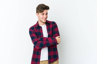 Beyaz arka planda izole edilmiş genç beyaz adam kollarını kavuşturarak gülümsüyor..