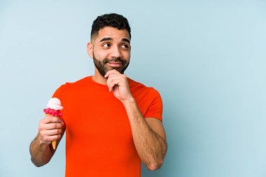 Dondurma tutan genç latin adam şüpheli ve şüpheci bir ifadeyle yanlamasına bakıyor..