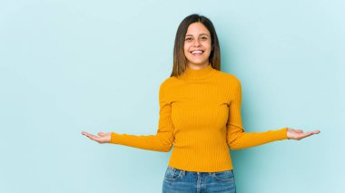 Mavi arka planda izole edilmiş genç bir kadın hoş bir ifade sergiliyor.