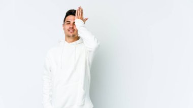 Beyaz arka planda izole edilmiş genç beyaz bir adam bir şeyi unutuyor. Alnına avuç içi ve gözlerini kapayarak vuruyor..