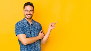 Sarı fırında izole edilmiş genç beyaz bir adam işaret parmağıyla işaret ederek gülümsüyor..