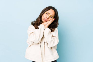 Genç, Latin kökenli bir kadın kendini izole etmiş esniyor. Ağzıyla ağzını kapatan yorgun bir hareket sergiliyor..