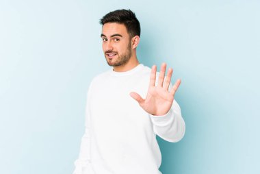 Mavi arka planda izole edilmiş genç beyaz adam tiksinti belirtisi gösteren birini reddediyor..