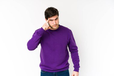 Beyaz arka planda izole edilmiş genç bir adam şakağı parmağıyla işaret ediyor, düşünüyor ve bir göreve odaklanıyor..