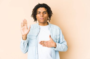 Genç Afrikalı Amerikalı Rasta adam yemin ediyor, elini göğsüne koyuyor..