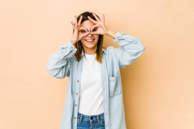 Bej arka planda izole edilmiş genç bir kadın gözlerde sorun olmadığını gösteriyor.