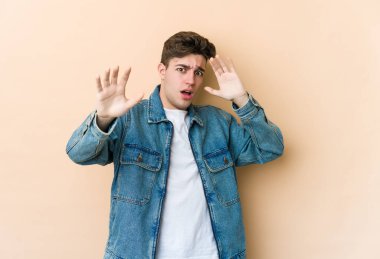 Beyazlı genç bir adam bej arka planda izole edildi. Yakın bir tehlike nedeniyle şoka girdi.