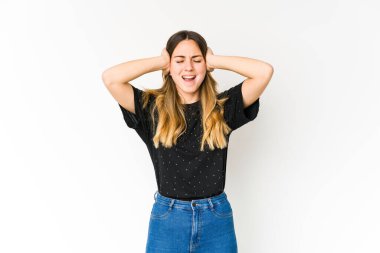 Beyaz arka planda izole edilmiş genç beyaz bir kadın. Kulakları kulaklarıyla kapatıyor. Çok fazla ses duymamaya çalışıyor..