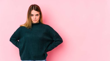 Pembe arka planda soyutlanmış beyaz bir kadın üzgün, ciddi bir yüz, mutsuz ve hoşnutsuz..