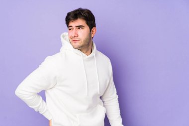 Mor arka planda izole edilmiş genç bir adam sırt ağrısı çekiyor..