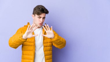 Mor arka planda izole edilmiş genç beyaz bir adam tiksinti belirtisi gösteren birini reddediyor..