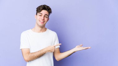 Mor arka planda izole edilmiş genç beyaz bir adam, elinde bir fotokopi alanı tutarken heyecanlanıyor..