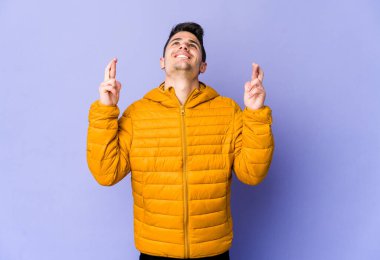 Mor arka planda izole genç beyaz adam şans dilemek için şans diliyor.