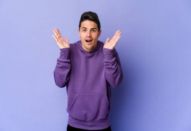 Mor arka planda izole genç beyaz adam şaşırdı ve şok oldu..