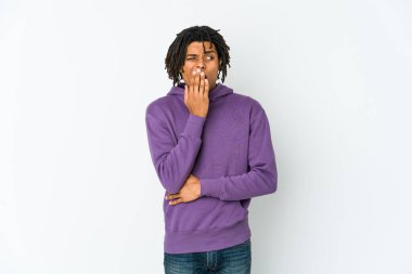 Genç Afrikalı Amerikalı Rasta adam esniyor. Ağzı eliyle kapatan yorgun bir jest gösteriyor..