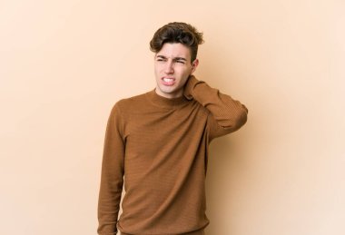 Beyazlı genç bir adam bej arka planda izole edilmiş. Oturaklı yaşam tarzından dolayı boyun ağrısı çekiyor..