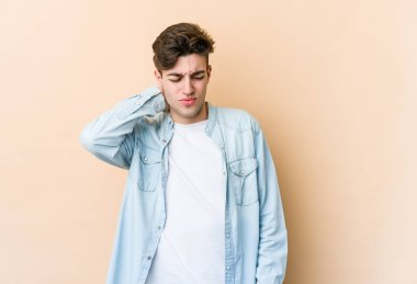 Beyazlı genç bir adam bej arka planda izole edilmiş. Oturaklı yaşam tarzından dolayı boyun ağrısı çekiyor..