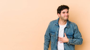 Bej arka planda izole edilmiş genç adam karnına dokunuyor, nazikçe gülümsüyor, yemek yiyor ve tatmin oluyor..