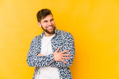 Sarı arka planda izole genç beyaz adam gülüyor ve eğleniyor..