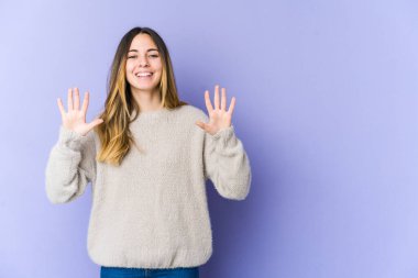 Mor arka planda izole edilmiş genç beyaz kadın on numarayı elleriyle gösteriyor..