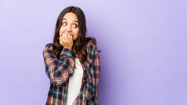 Latin kökenli genç bir kadın tırnak yiyor, gergin ve endişeli..