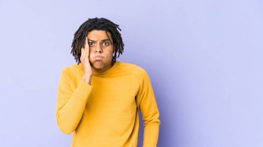 Rasta saç stili giyen genç siyahi adam yanakları siliyor, yorgun bir ifade takınıyor. Yüz ifadesi kavramı.