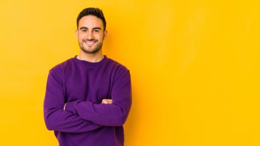 Sarı fırında izole edilmiş genç beyaz adam kendini güvende hissediyor, kararlılıkla kollarını kavuşturuyor..