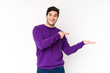 Beyaz arka planda izole edilmiş genç bir adam, avuç içinde bir kopya alanı tutarken heyecanlı..