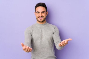 Mor arka planda izole edilmiş beyaz bir genç hoş bir yüz ifadesi sergiliyor..