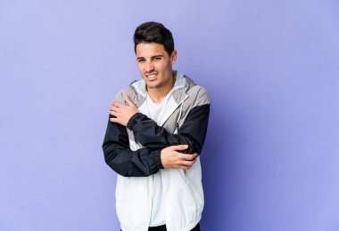 Genç beyaz adam mor arka planda izole edilmiş dirsek masajı yapıyor, kötü bir hareketin ardından acı çekiyor..