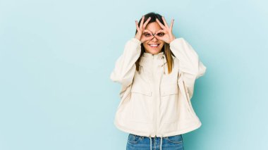 Mavi arka planda izole edilmiş genç bir kadın, gözlerde sorun olmadığını gösteriyor.