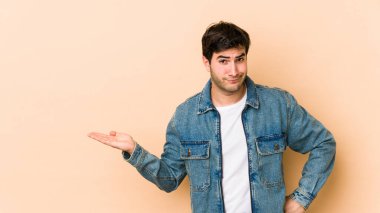 Bej arka planda izole edilmiş genç bir adam bir avuç içinde fotokopi alanı ve belinde bir el daha gösteriyor..