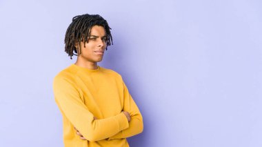 Rasta saç stili giyen, hoşnutsuzca kaşlarını çatan, kollarını kavuşturan genç siyahi bir adam..