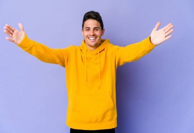 Mor arka planda izole olmuş genç beyaz bir adam zaferi ya da başarıyı kutluyor, şaşırıyor ve şok oluyor..