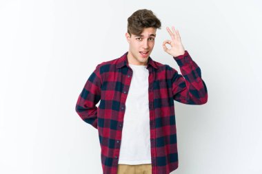Beyaz arka planda izole edilmiş genç beyaz bir adam bir göz kırptı ve elleriyle iyi bir jest yaptı..