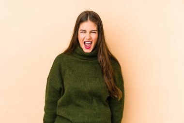 Beyazlı genç bir kadın bej arka planda izole edilmiş çok kızgın, öfkeli, hayal kırıklığına uğramış bağırıyor..