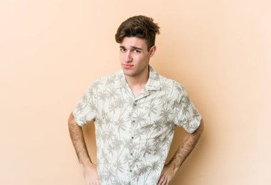 Kafkasyalı genç adam bej arka planda izole, kafası karışmış, şüpheli ve güvensiz hissediyor..